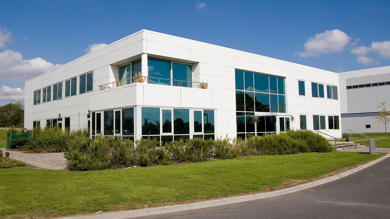 Et hvitt forretningsbygg omgitt av gress og blå himmel