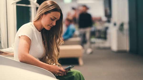 Ung dame sitter og ser på mobilen sin